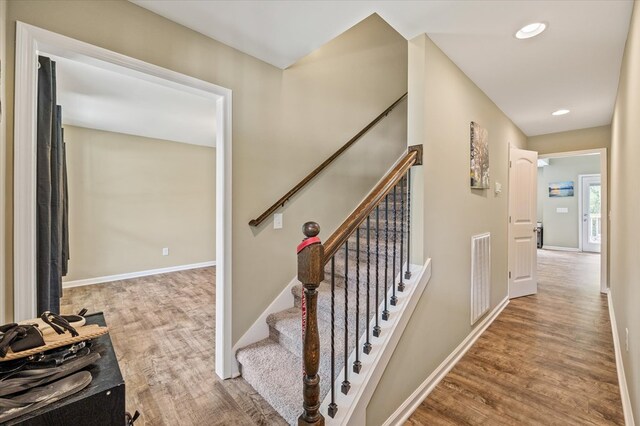 staircase with baseboards, visible vents, and wood finished floors