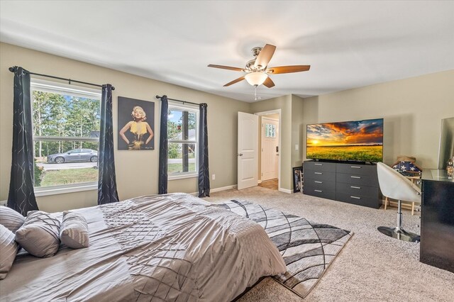 bedroom with a ceiling fan, light carpet, and baseboards