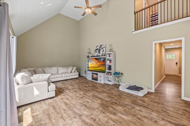 living room with ceiling fan, high vaulted ceiling, and wood finished floors