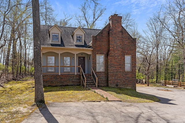 view of front of property featuring driveway, covered porch, brick siding, a shingled roof, and a chimney