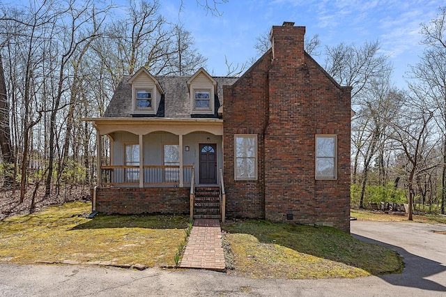 view of front facade with a front lawn, a chimney, a porch, and brick siding