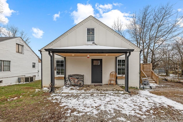 bungalow with covered porch, central AC, and board and batten siding