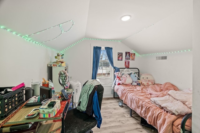 bedroom featuring lofted ceiling, light wood-style flooring, and visible vents