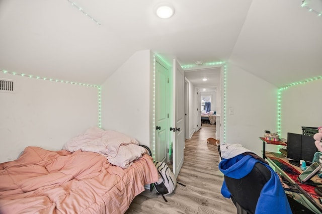 bedroom with light wood-type flooring, visible vents, and vaulted ceiling