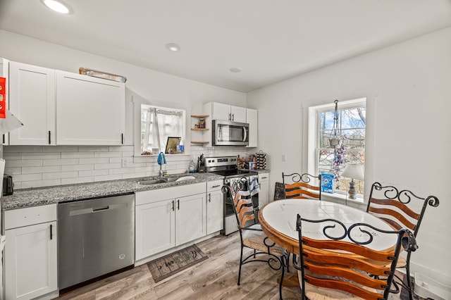 kitchen featuring appliances with stainless steel finishes, white cabinets, and a sink