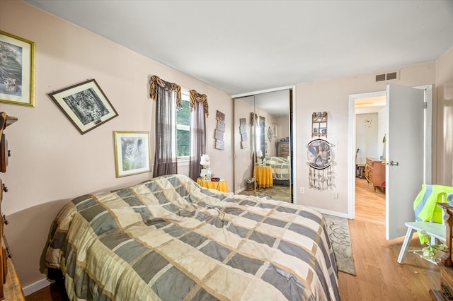 bedroom featuring light wood finished floors, a closet, visible vents, and baseboards