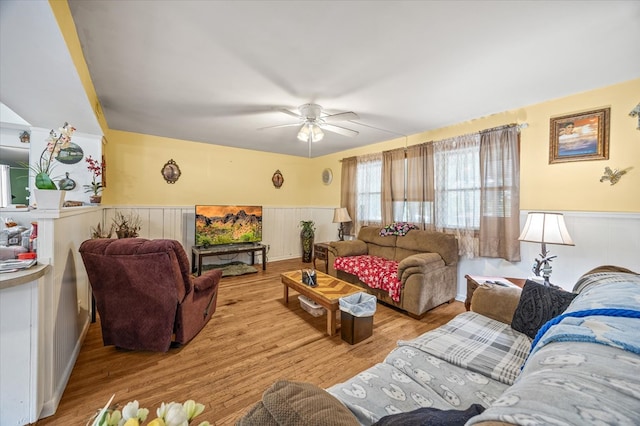 living area featuring ceiling fan, wainscoting, and light wood-style flooring