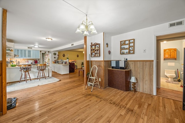 dining room featuring a wainscoted wall, light wood-style flooring, visible vents, and wood walls