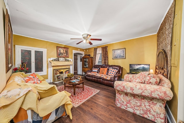 living area with a fireplace, ceiling fan, and wood finished floors