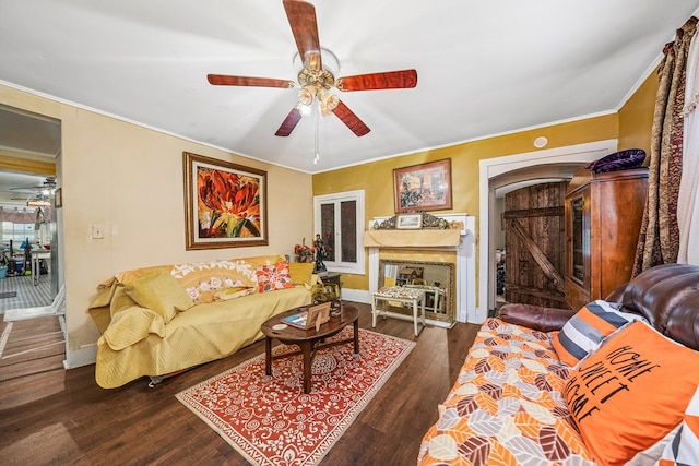 living area with dark wood-type flooring, ornamental molding, a fireplace, and ceiling fan