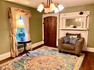 living area with an inviting chandelier, wood finished floors, baseboards, and arched walkways