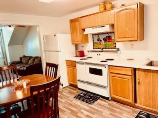 kitchen with under cabinet range hood, light wood-type flooring, white appliances, and light countertops