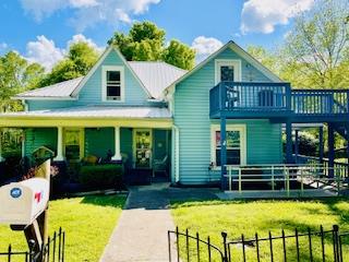 view of front of property with a porch, metal roof, a front lawn, and fence