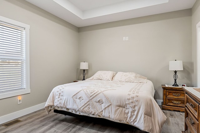 bedroom with visible vents, multiple windows, baseboards, and light wood finished floors