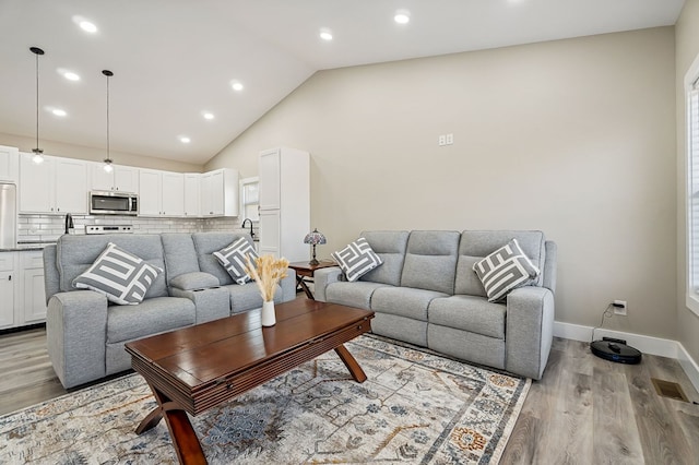 living room with recessed lighting, visible vents, baseboards, and light wood-style flooring