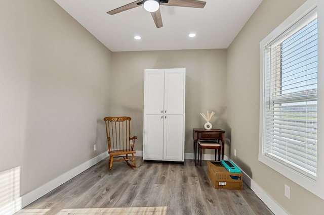 sitting room featuring a ceiling fan, light wood-style floors, baseboards, and a wealth of natural light