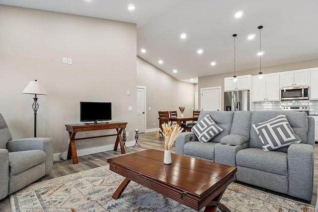 living area featuring light wood finished floors, recessed lighting, high vaulted ceiling, and baseboards