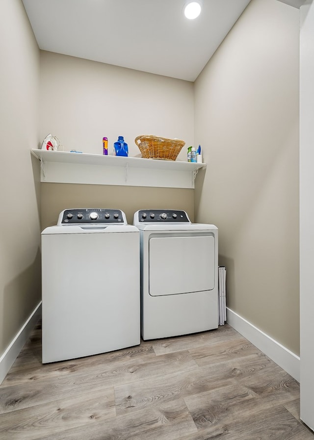 clothes washing area with washer and clothes dryer, laundry area, baseboards, and wood finished floors