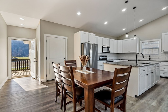 kitchen featuring a center island with sink, a sink, vaulted ceiling, appliances with stainless steel finishes, and backsplash