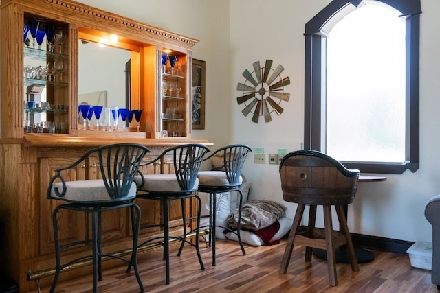 bar with a dry bar, baseboards, arched walkways, and wood finished floors