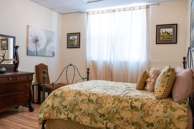 bedroom featuring light wood-type flooring and a paneled ceiling