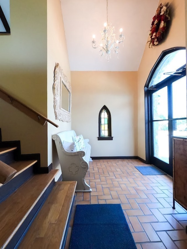 foyer with stairs, brick floor, a wealth of natural light, and baseboards