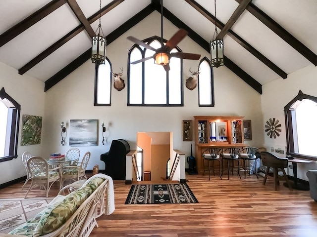 living area featuring high vaulted ceiling, a wealth of natural light, a ceiling fan, and wood finished floors