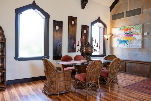 dining area with vaulted ceiling, wood finished floors, visible vents, and baseboards