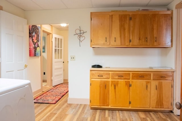 kitchen with a paneled ceiling, light wood finished floors, and light countertops