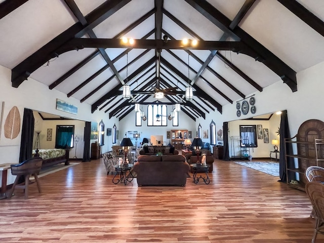 living room featuring a skylight, a ceiling fan, wood finished floors, high vaulted ceiling, and beam ceiling