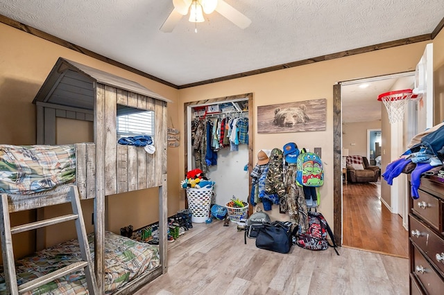 bedroom featuring a textured ceiling, crown molding, a closet, and light wood-style floors