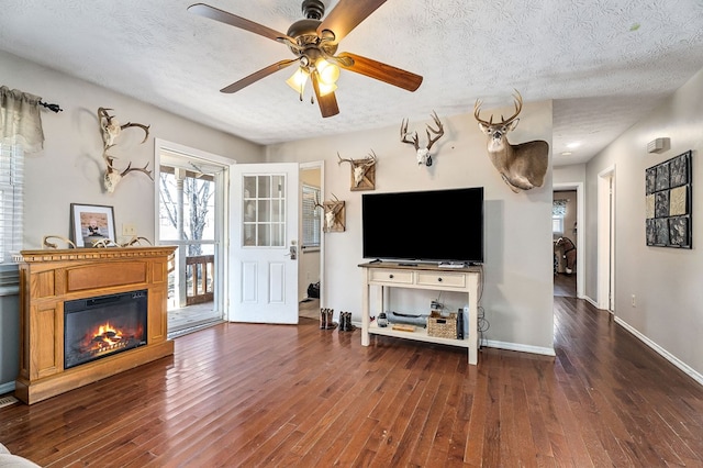 unfurnished living room with a textured ceiling, a glass covered fireplace, and dark wood finished floors