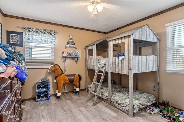 bedroom with multiple windows, crown molding, a textured ceiling, and wood finished floors