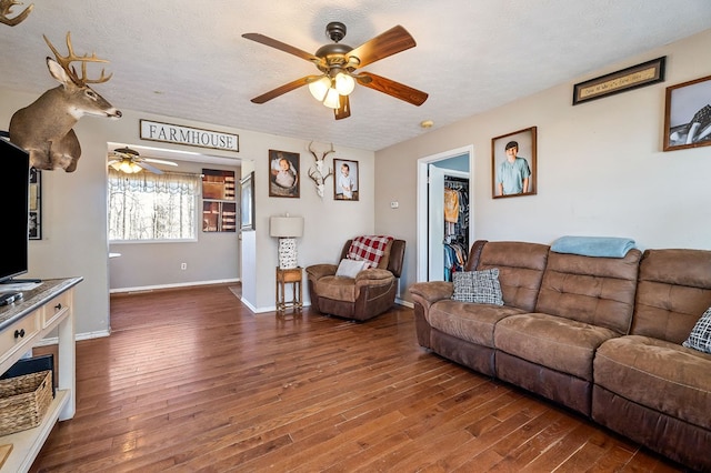 living room with dark wood-style floors, a ceiling fan, baseboards, and a textured ceiling