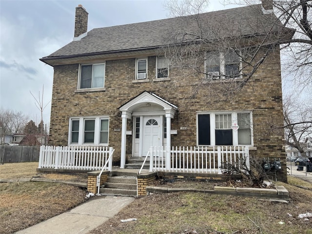 1943 Central St, Detroit, MI 48209 - colonial house featuring a chimney, brick siding, a shingled roof, and a porch