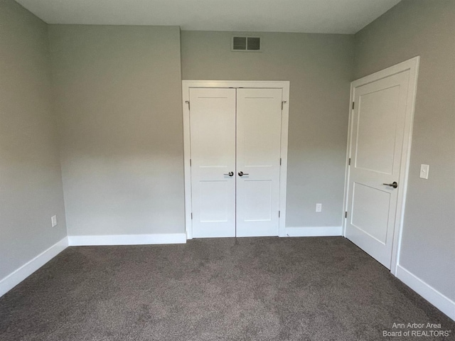 unfurnished bedroom featuring dark carpet and a closet