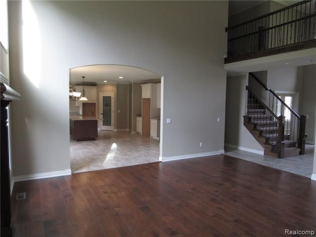 72859 Sorrel Dr, Bruce, MI 48065 - unfurnished living room with a high ceiling, wood finished floors, arched walkways, baseboards, and stairway