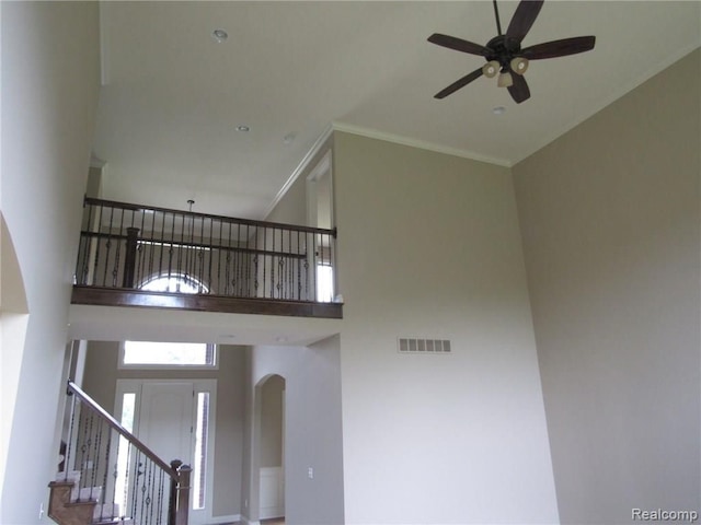 interior space featuring a high ceiling, ceiling fan, and crown molding