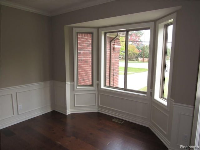 empty room with ornamental molding and dark wood-type flooring