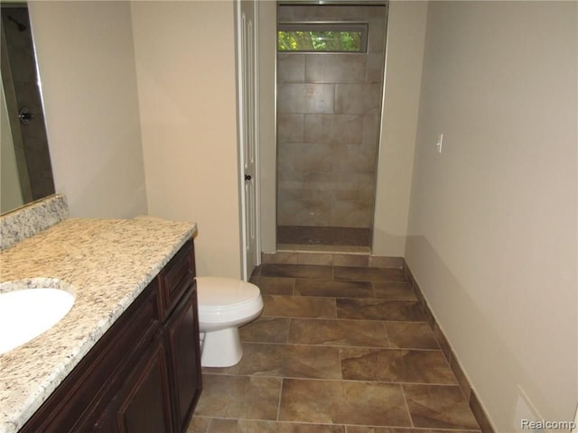 bathroom featuring vanity, toilet, and a tile shower