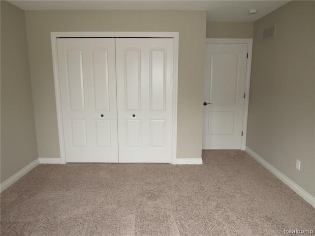 unfurnished bedroom featuring light colored carpet and a closet