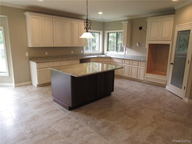 kitchen with light stone countertops, sink, crown molding, decorative light fixtures, and a kitchen island