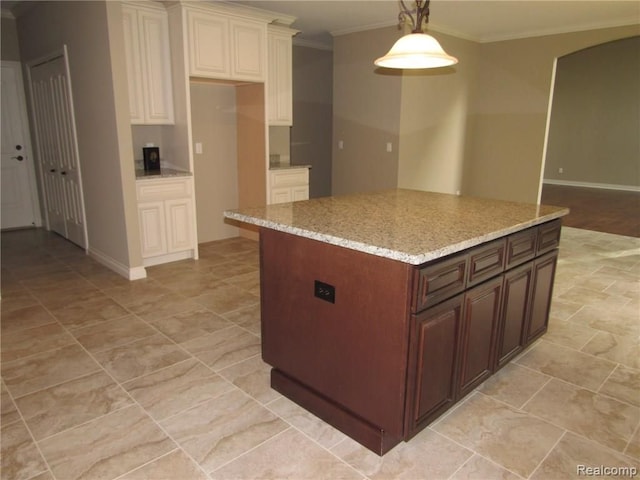 kitchen with light stone countertops, crown molding, a kitchen island, and hanging light fixtures