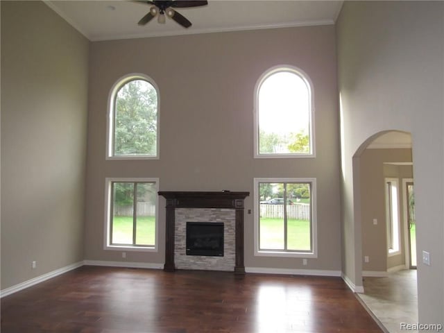 unfurnished living room featuring plenty of natural light, dark hardwood / wood-style floors, a fireplace, and ceiling fan