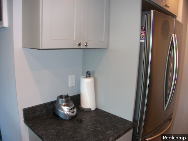 kitchen with white cabinets, stainless steel fridge, and dark stone countertops