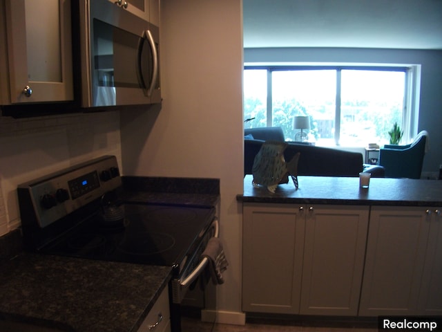 kitchen featuring appliances with stainless steel finishes, a wealth of natural light, and dark stone countertops