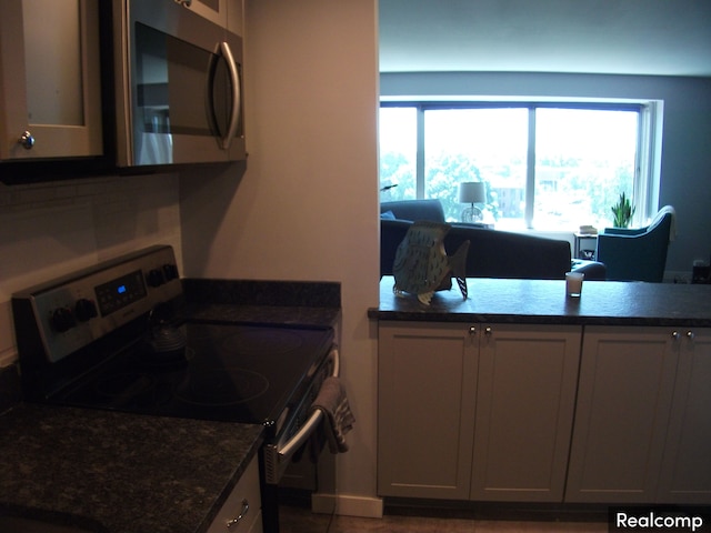 kitchen featuring a wealth of natural light, dark stone counters, and appliances with stainless steel finishes