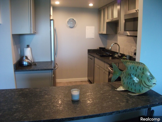 kitchen featuring decorative backsplash, sink, stainless steel appliances, and dark stone counters