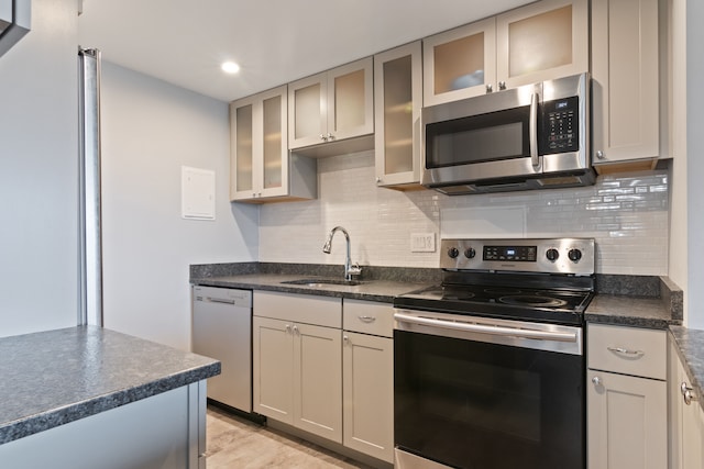 kitchen with appliances with stainless steel finishes, light hardwood / wood-style floors, tasteful backsplash, and sink