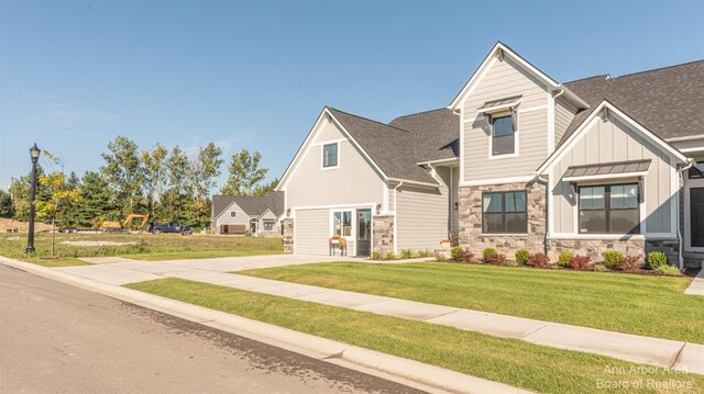 9 Black Cherry Ln, Saline, MI 48176 - craftsman house with board and batten siding, stone siding, a front yard, and roof with shingles